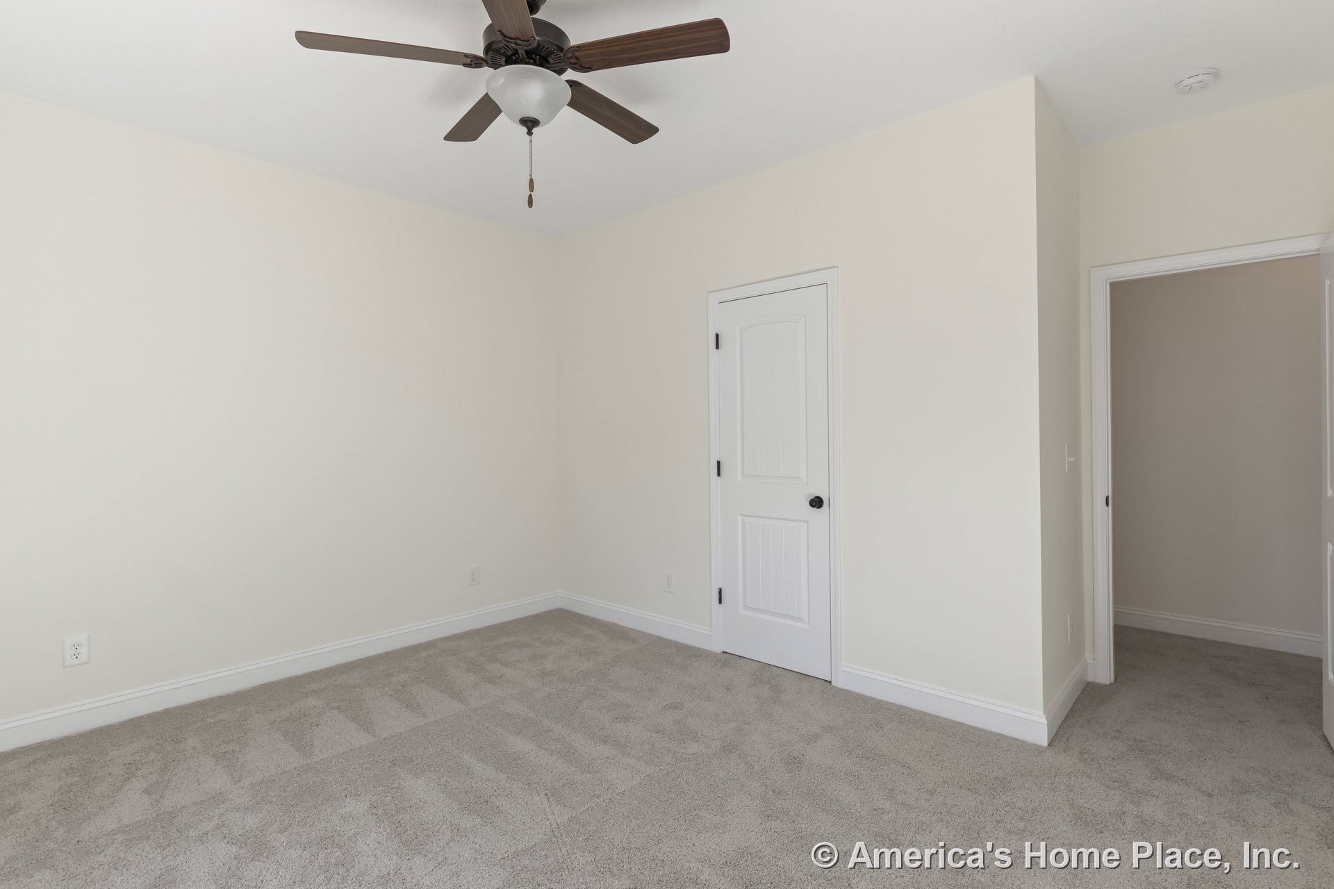 Bedroom with light carpet flooring, ceiling fan and light fixture, white paneled closet and entry doors, neutral wall color, and baseboard trim.