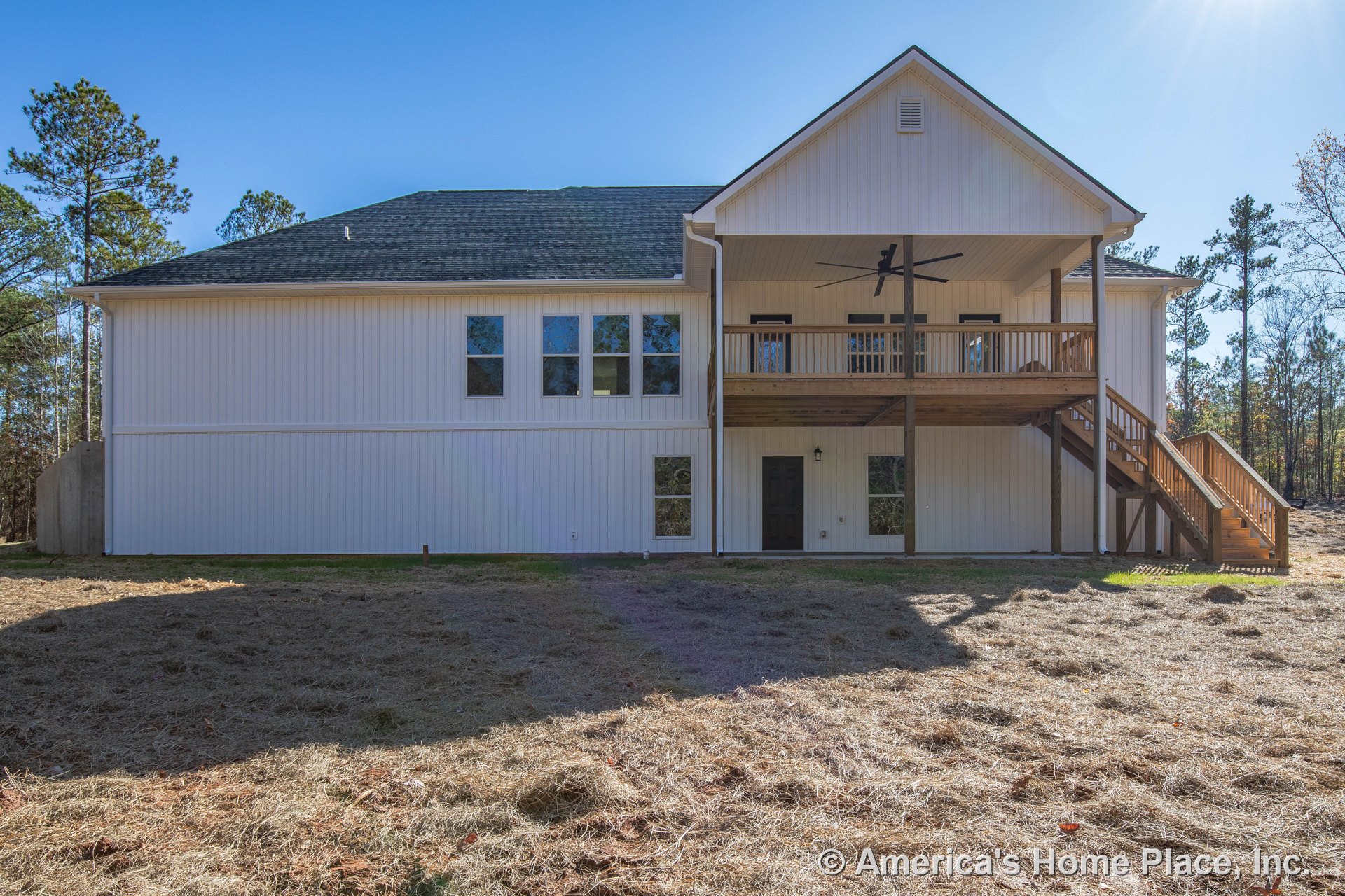 Two-story home with white vertical siding, multiple rectangular windows, covered upper porch featuring wood railings, ceiling fan, exterior staircase, dark trim and exterior door