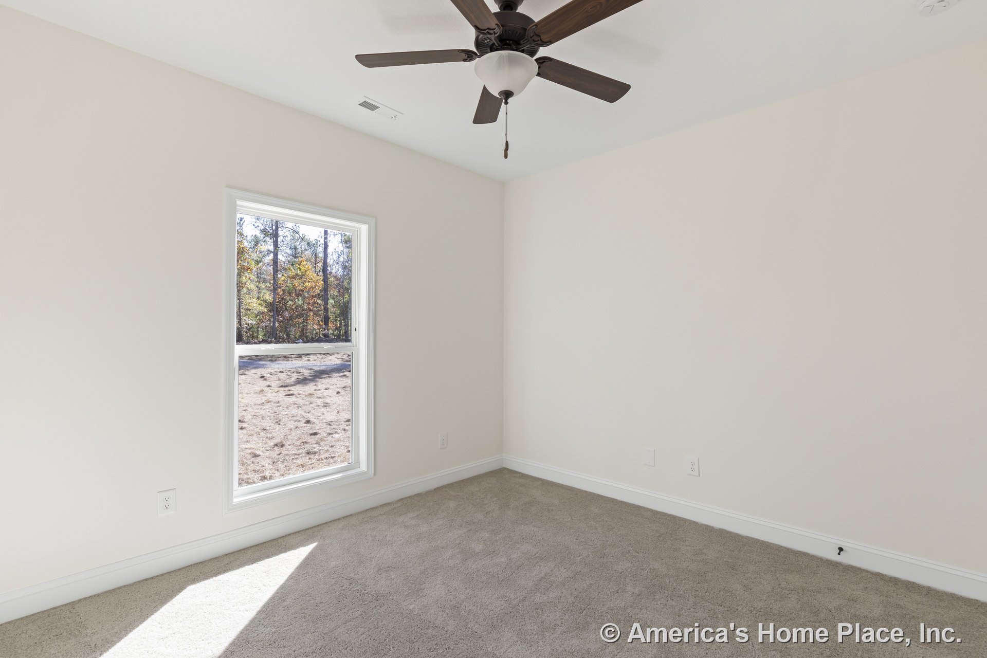 Bedroom with single large window framed in white trim, beige carpet flooring, ceiling fan with integrated light fixture, neutral painted walls, white baseboards, and visible