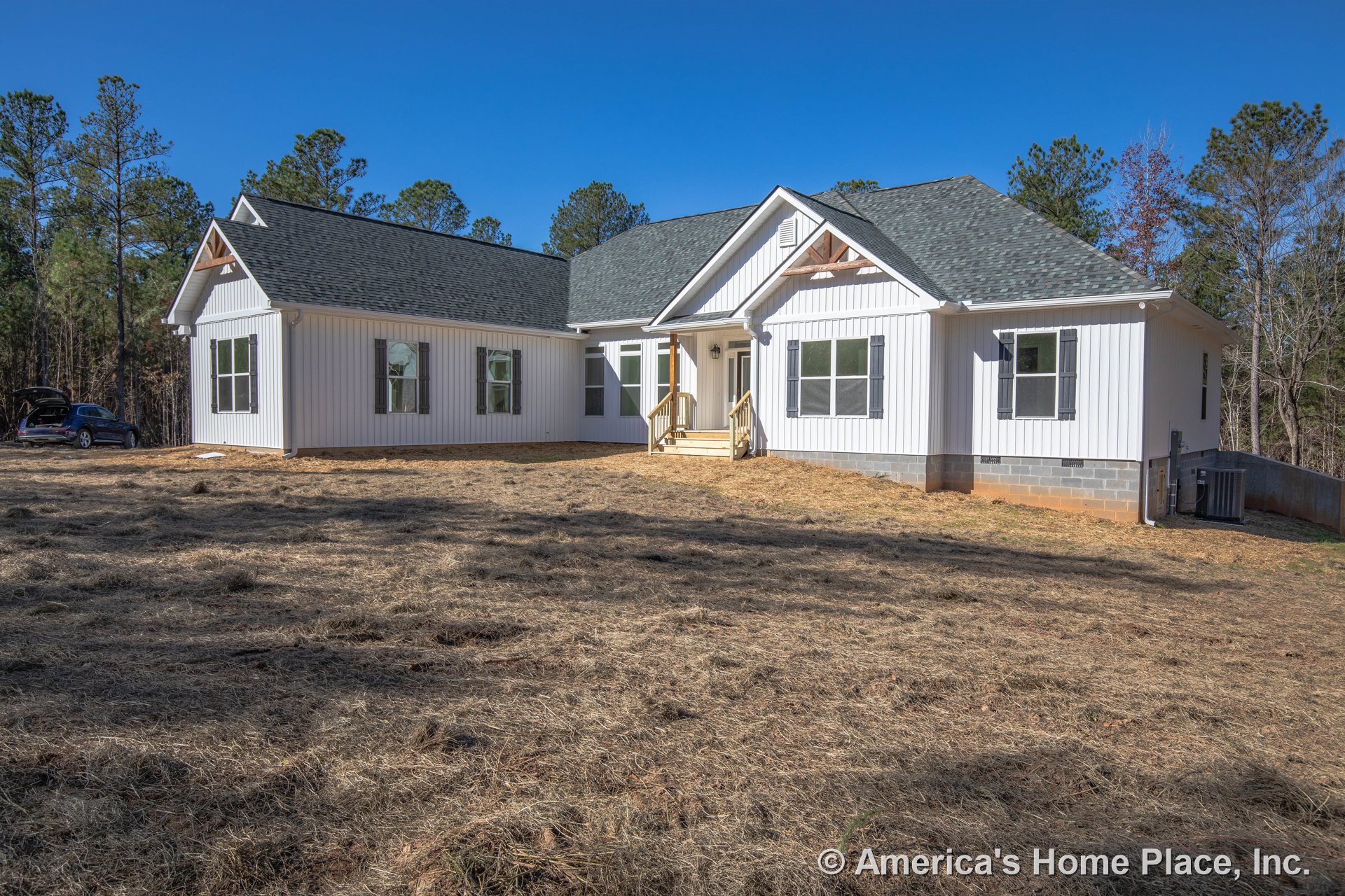 White vertical siding and black shutters on a custom home exterior with a covered front porch, wood steps, gable roof with asphalt shingles, multiple double-hung windows, and