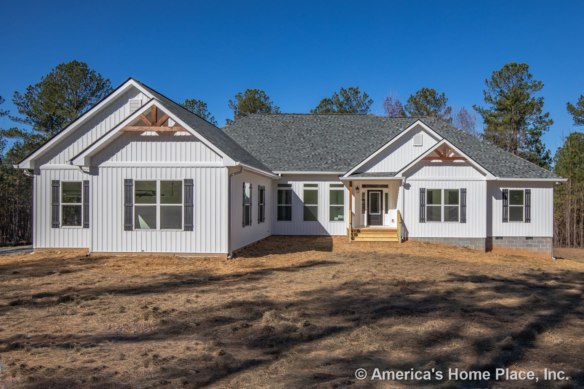 White vertical siding exterior with gable roofs topped by asphalt shingles, large windows framed by dark shutters, covered front porch with wooden steps, and decorative gable