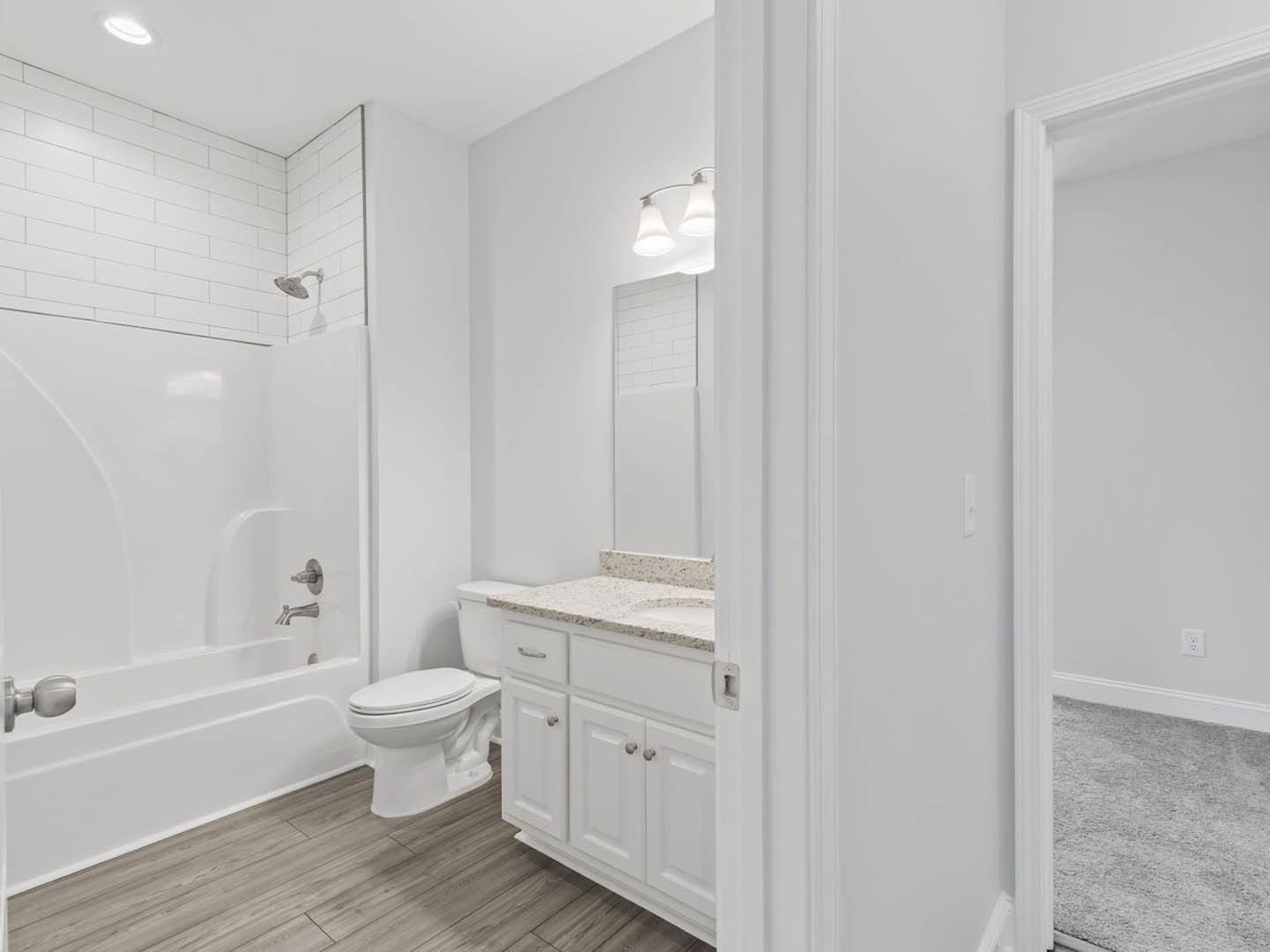 Modern bathroom featuring white tile flooring, a glass-enclosed shower, white toilet with seat down, white cabinetry, brushed metal door knob, and contemporary light fixture