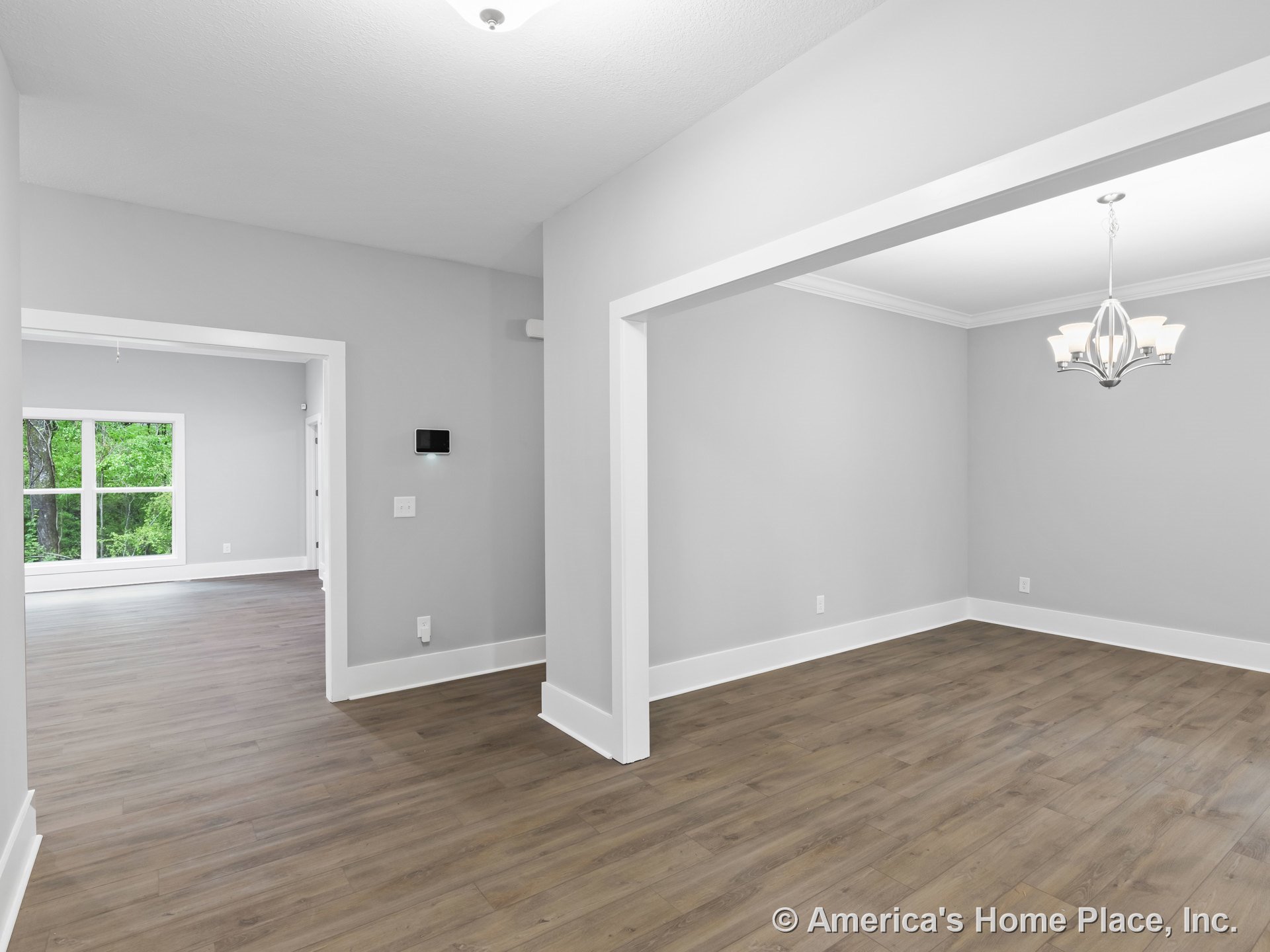 Open dining room with wood-look plank flooring, gray painted walls, large interior windows, white baseboards and trim, and a contemporary ceiling chandelier.