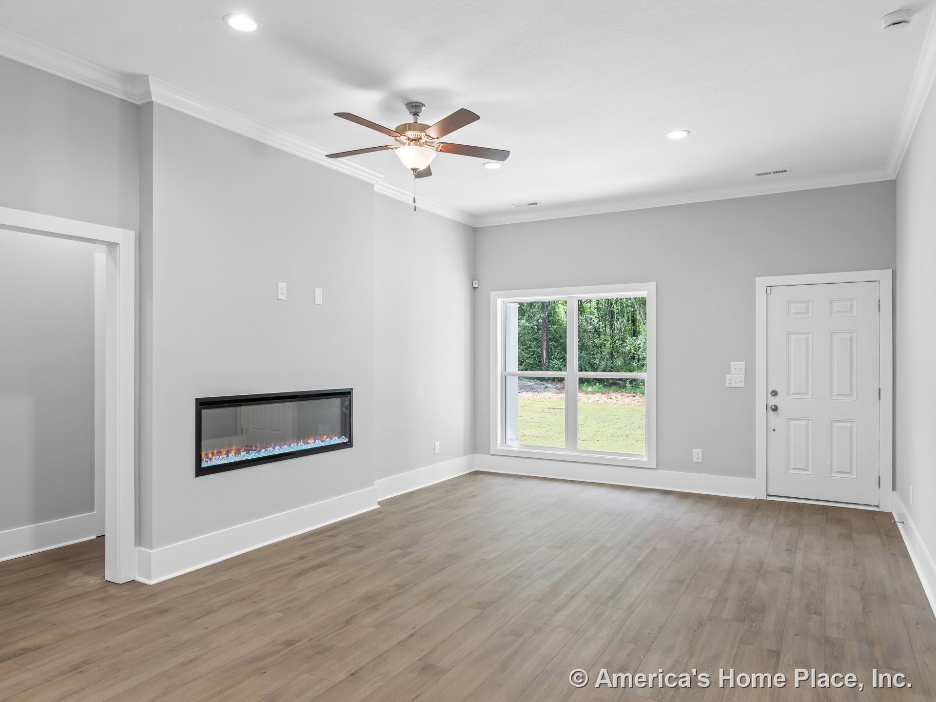 Modern living room with linear electric fireplace, expansive double-pane window, wood-look plank flooring, white trim and baseboards, ceiling fan with integrated light, recessed