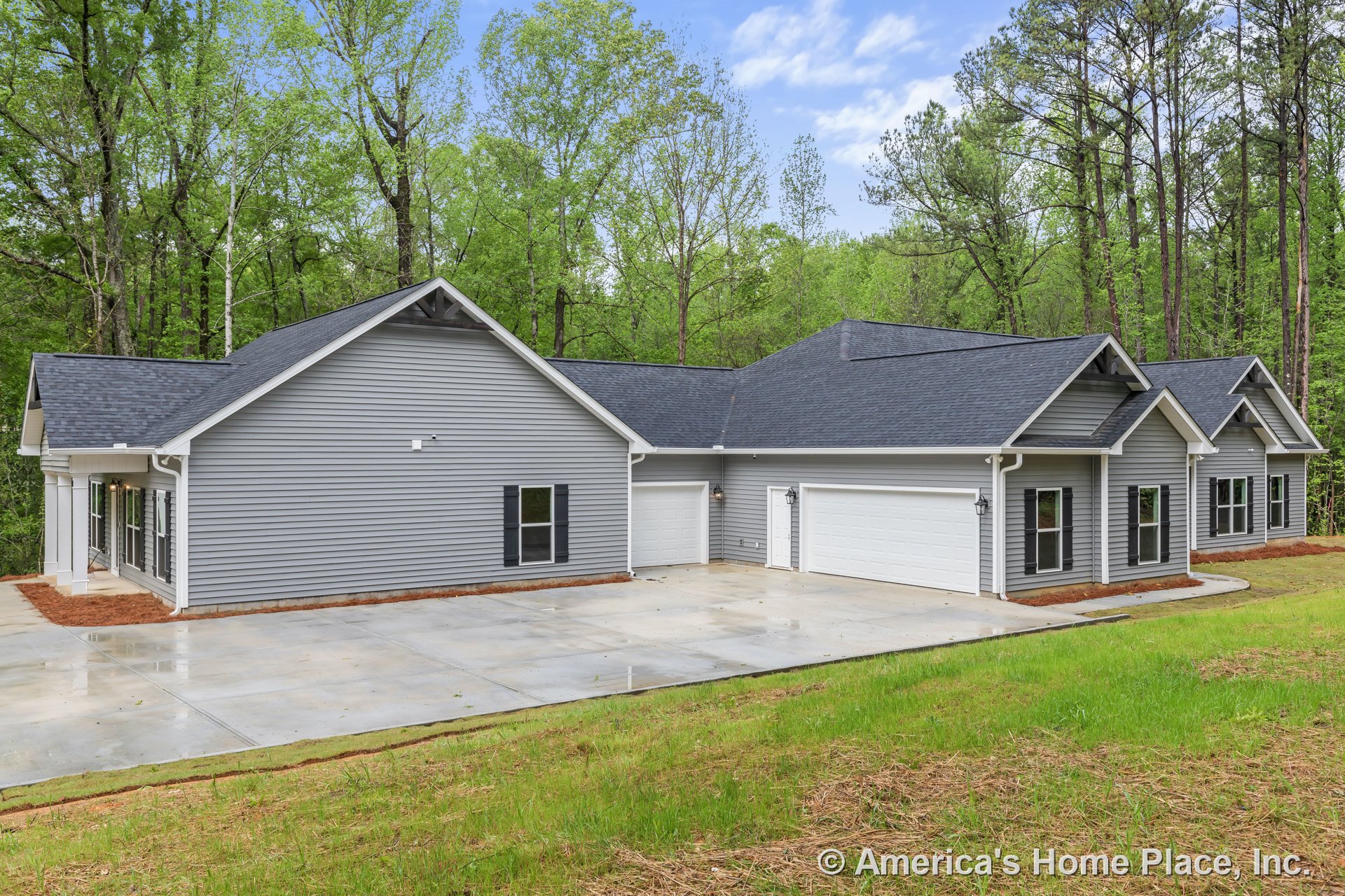 Gray vinyl siding exterior with multiple gabled roofs, black shingles, three-car garage featuring white doors, concrete driveway, black shutters, white trim, covered entry, outdoor