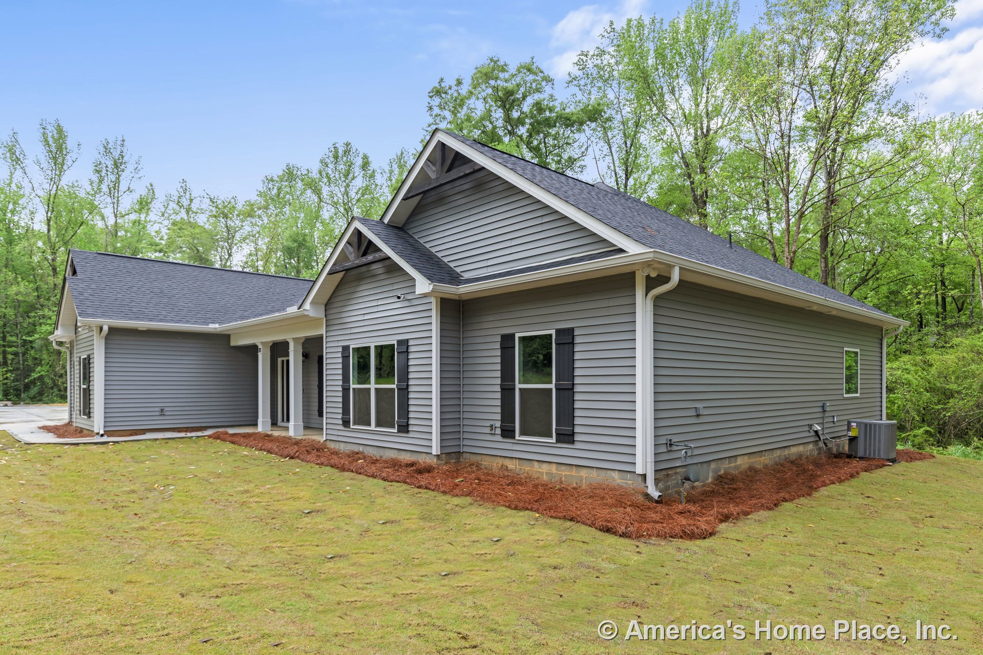 Gray vinyl siding exterior with black window shutters, covered front porch supported by columns, white trim and gutters, architectural roof shingles, and double-pane windows on a