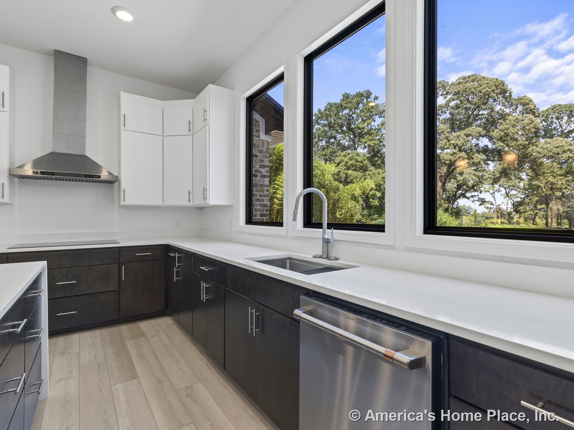 Kitchen with large black-framed windows, white upper cabinets, dark lower cabinets, white quartz countertops, stainless steel range hood and dishwasher, undermount sink with