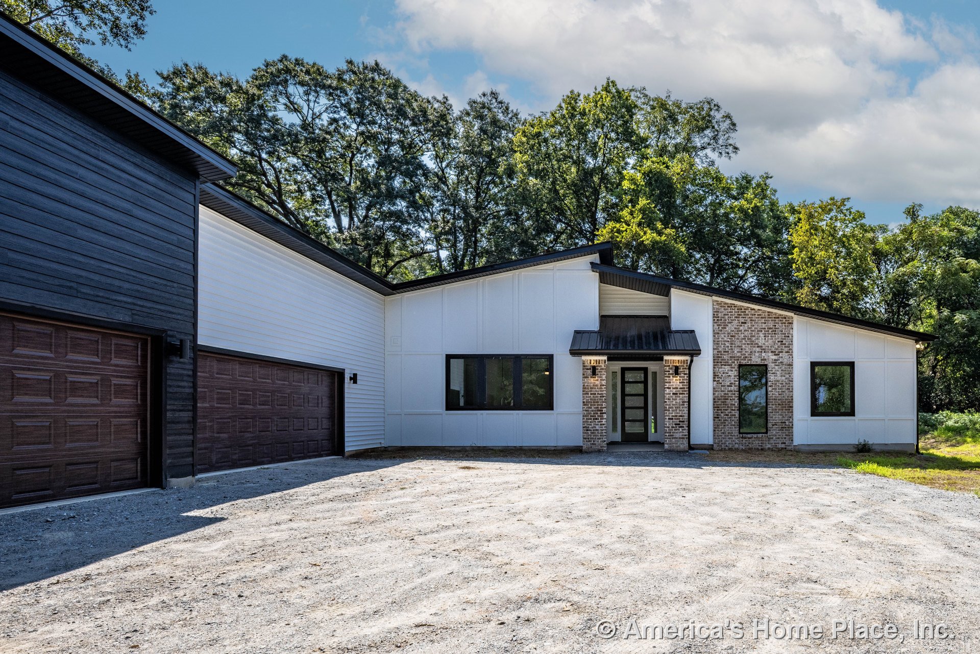 Modern single-story home with mixed brick and white siding facade, three black garage doors, large black-framed windows, covered front entry with metal awning, sloped rooflines