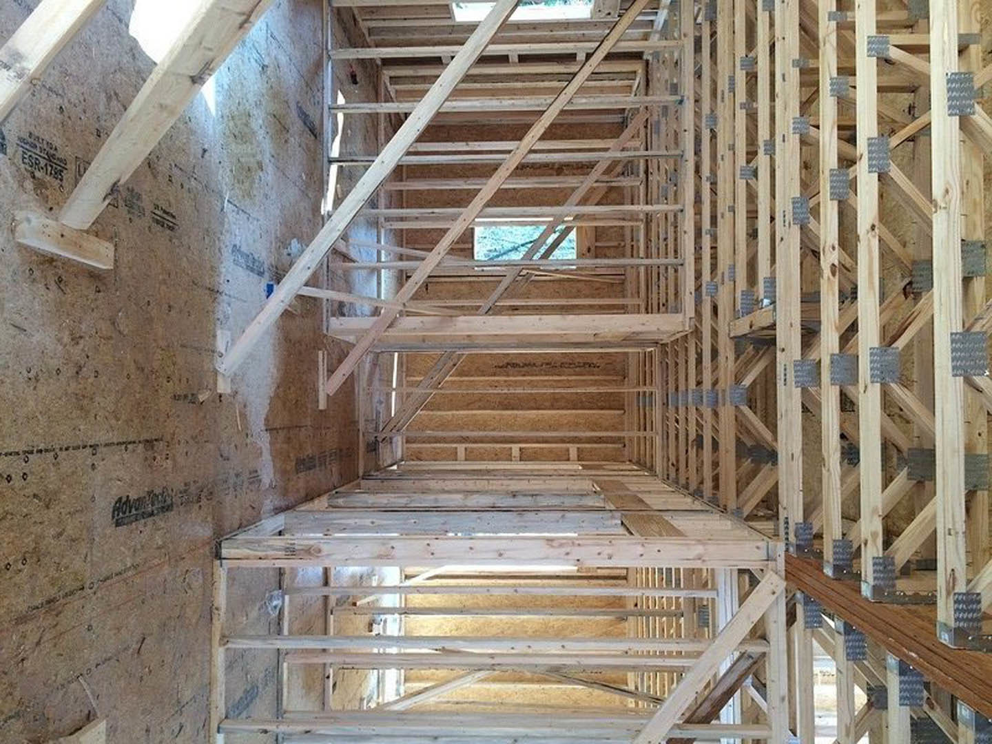 Exposed wooden beams and framing inside a house under construction, unfinished lumber forming walls and ceiling structure