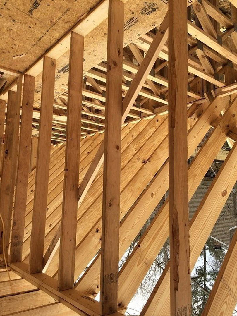 Exposed wooden beams and trusses forming the structural frame of a house under construction