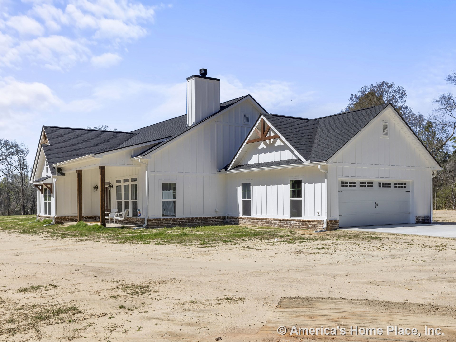 White board and batten siding with brick foundation trim, black shingle gable roof, large windows, covered front porch supported by wood columns, attached two-car garage with white