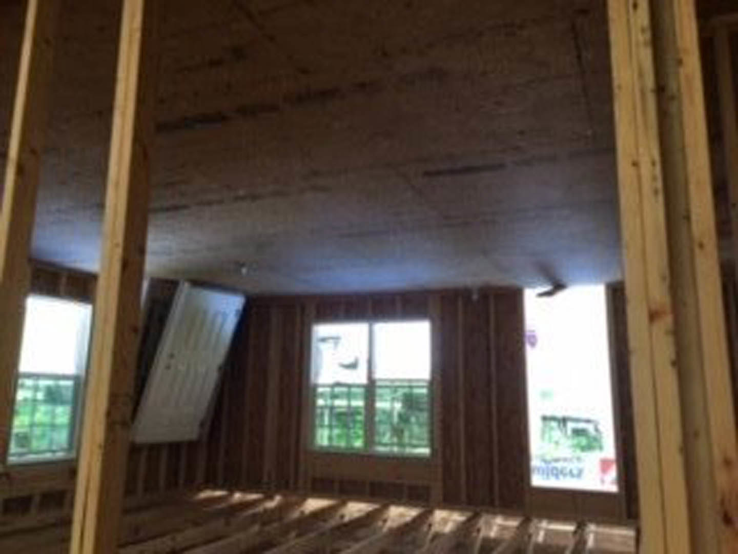 Living room with exposed wood ceiling beams, white walls, large window with outdoor view, and white door featuring a circular cutout.