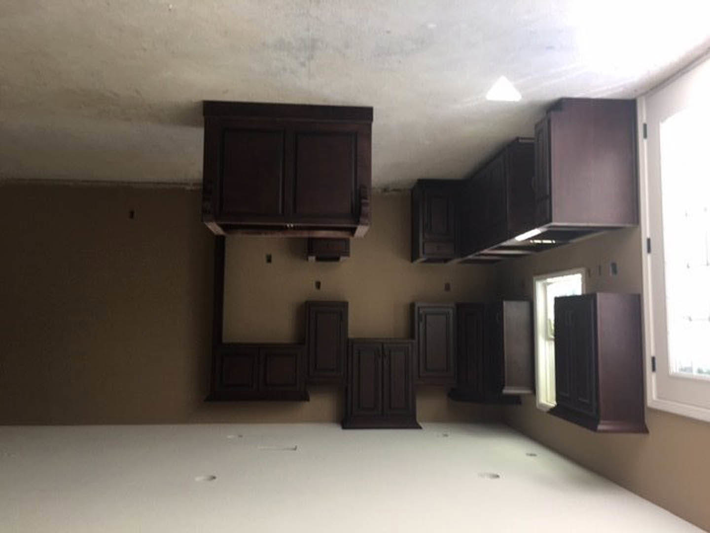Kitchen with dark brown cabinets, white countertops, stainless steel appliances, and large windows letting in natural light