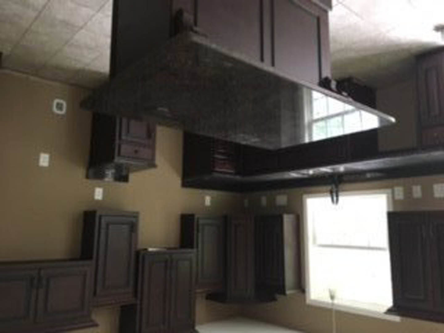 Modern kitchen featuring white shaker cabinets, stainless steel range hood, light stone countertops, and neutral painted walls