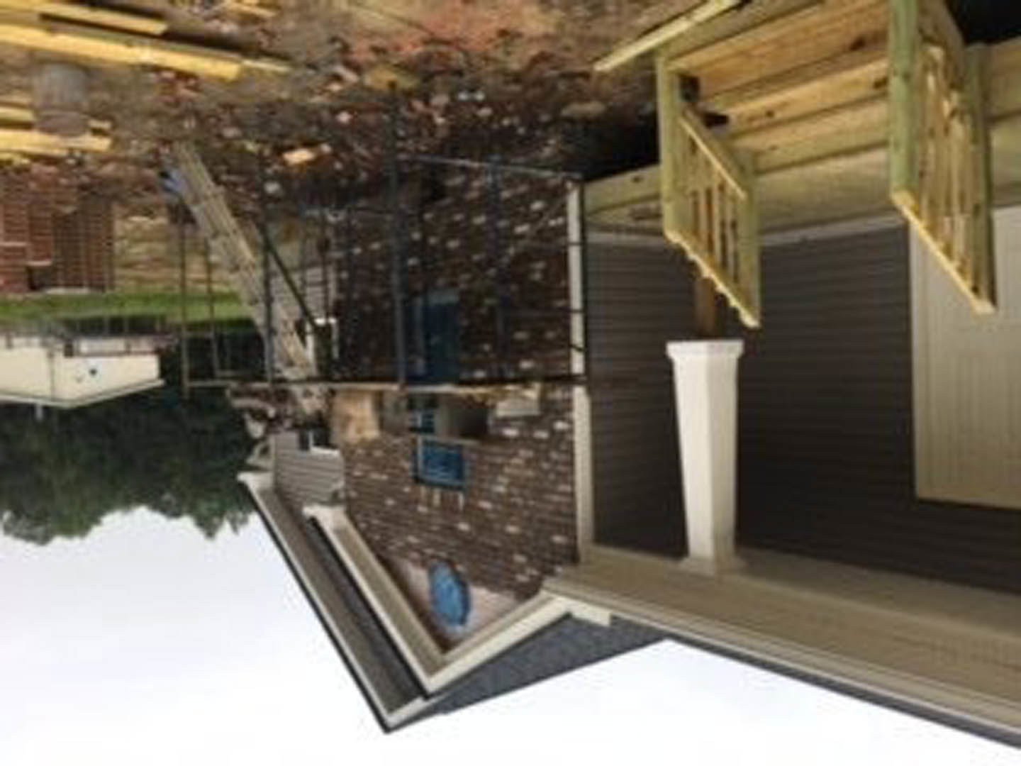 Unfinished interior with exposed drywall, wooden staircase, and construction materials scattered on floor