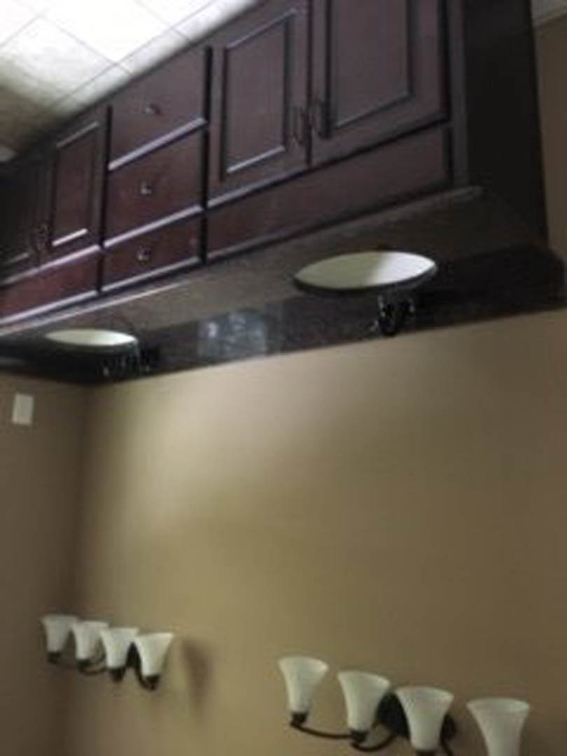 Modern kitchen with white cabinetry, stainless steel sink, open wood shelf, light stone countertops, and stainless steel range hood