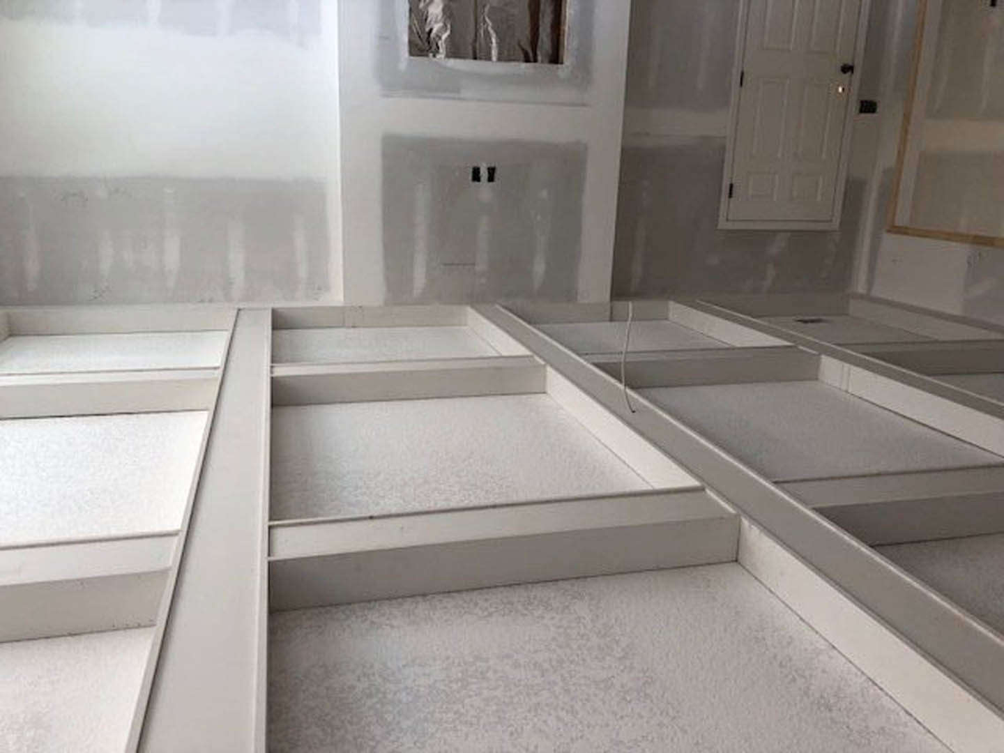 Bathroom with white plaster walls and ceiling, white door featuring black knobs, marble tile flooring, and granite tub surround.
