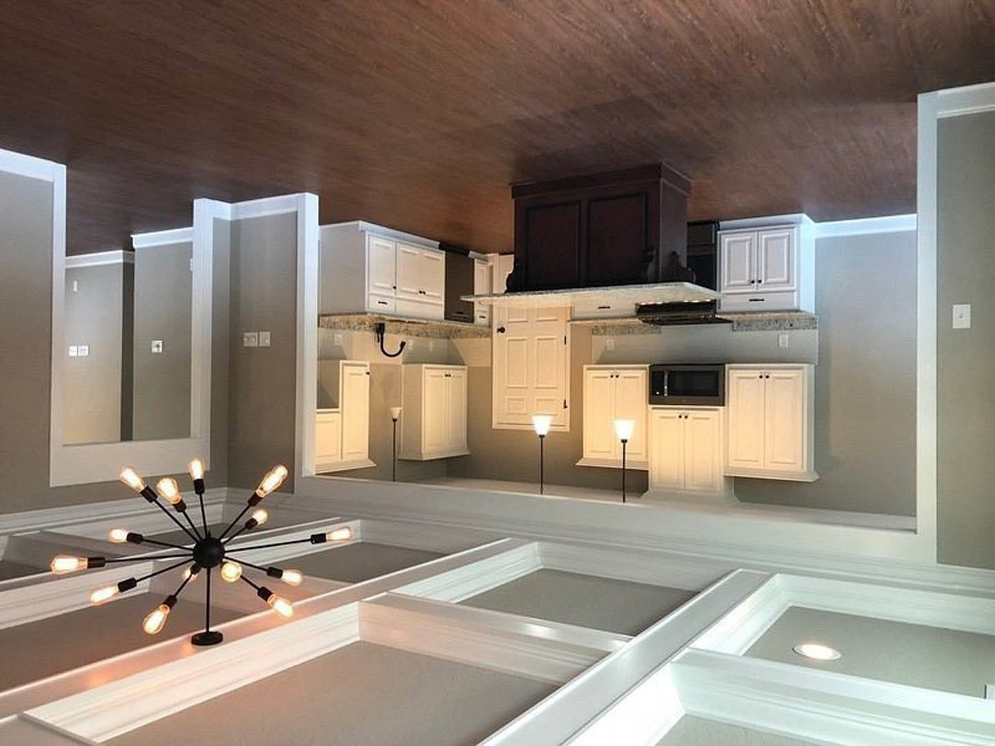 White kitchen cabinets, marble countertops, tile backsplash, stainless steel sink, and a crystal chandelier hanging from the ceiling