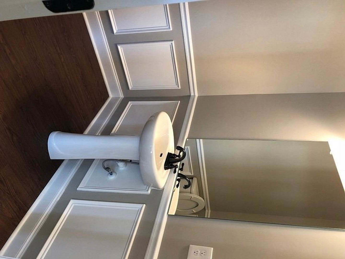 White rectangular sink with black border set against plaster wall, chrome faucet, and black soap dispenser on countertop in modern bathroom.