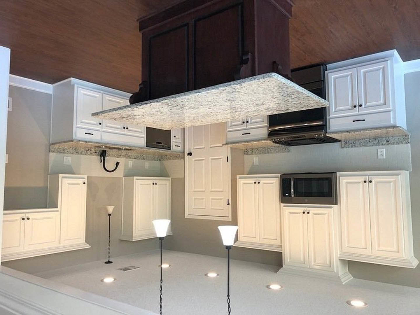 White kitchen cabinets with marble countertop, built-in microwave, black pendant light fixture, and smooth white surfaces