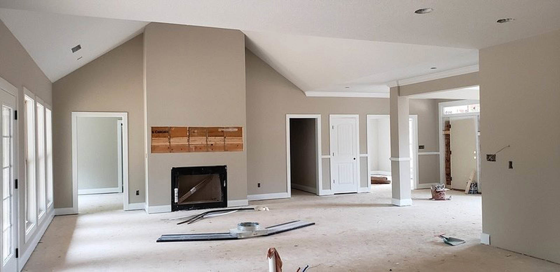 Living room featuring a stone fireplace, light hardwood flooring, white plaster walls, and recessed ceiling lighting