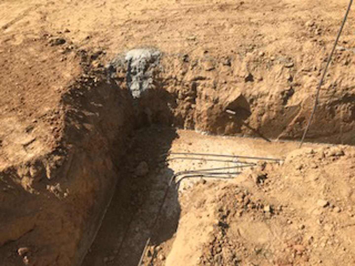 Excavated dirt mound with a large hole, surrounded by soil and construction tracks