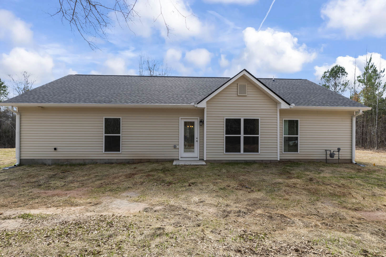 Two-story home with white siding, white-framed windows, glass-paneled front door, black metal railing, and green grass lawn under a clear blue sky
