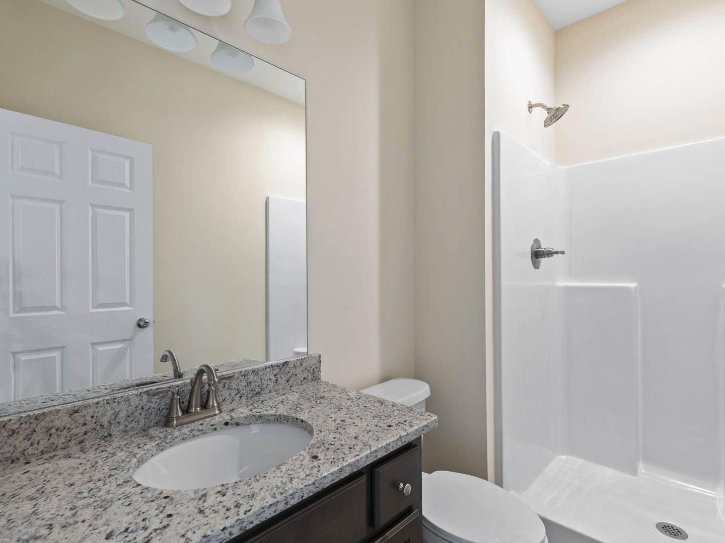 Modern bathroom featuring white tile walls, a glass shower enclosure with chrome fixtures, a sleek vanity with integrated sink and faucet, and a white toilet adjacent to a paneled