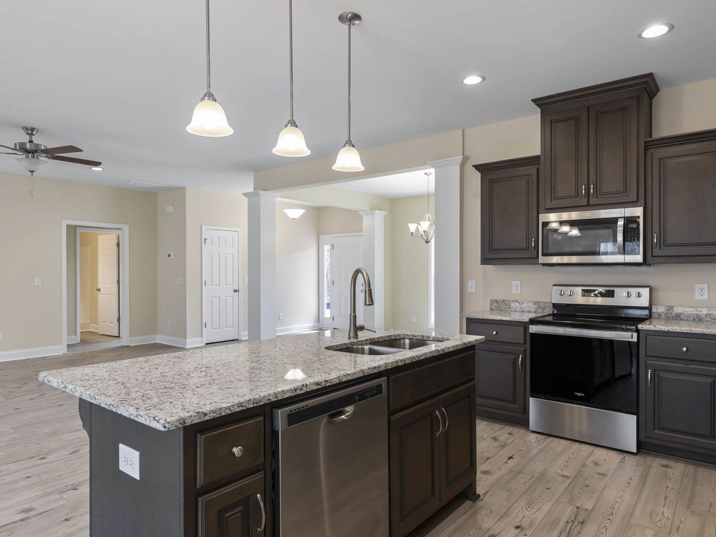 Granite island with stainless steel oven and dishwasher, white cabinetry, silver hardware, and wall outlet in modern kitchen