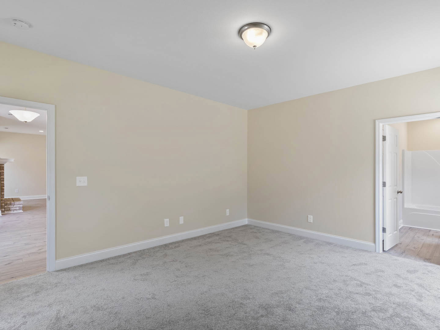Carpeted room with white walls, white door featuring a silver doorknob, and ceiling-mounted light fixture
