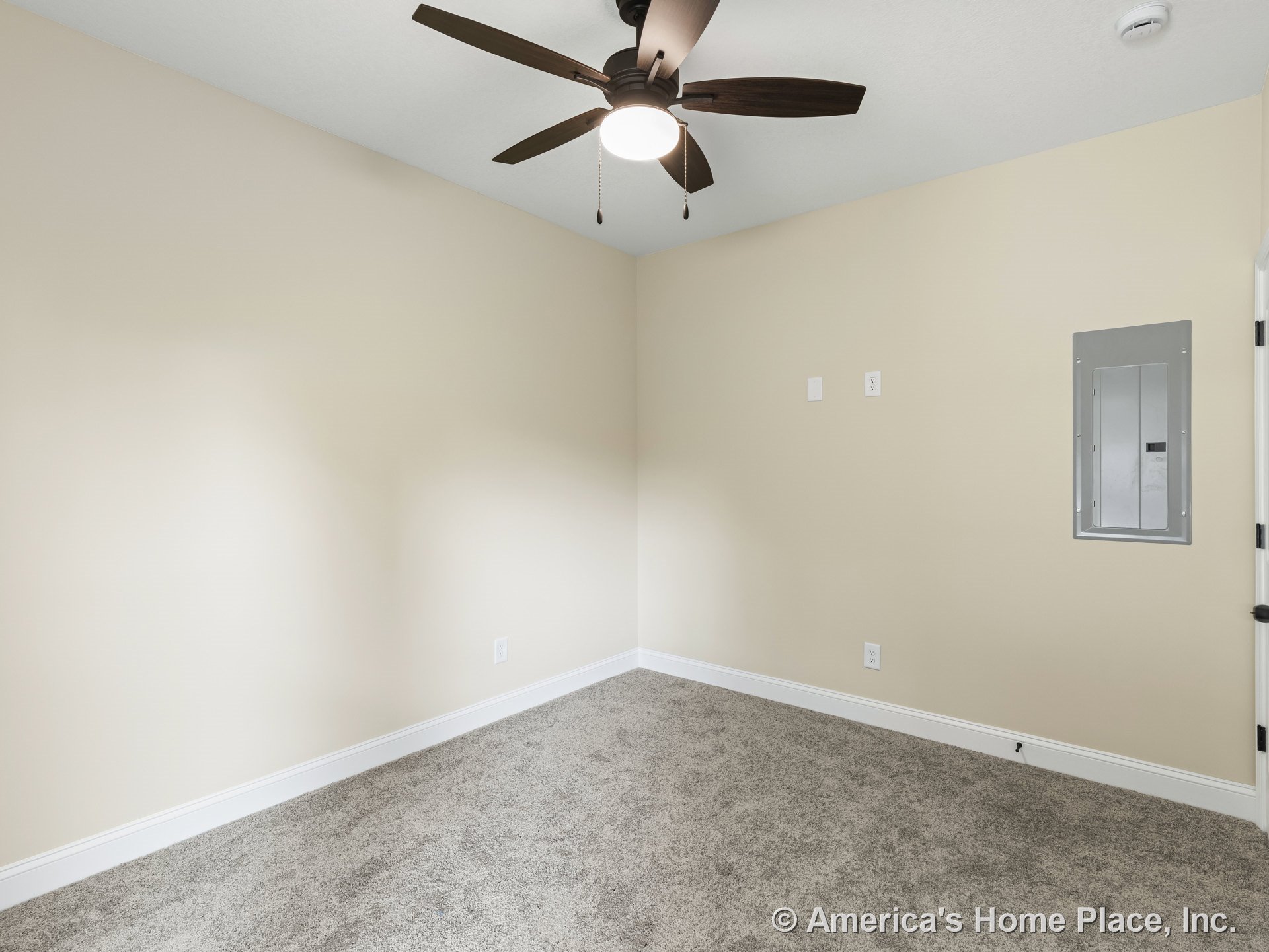 Beige painted walls with white baseboard trim, carpet flooring, ceiling fan with integrated light fixture, electrical panel, and smoke detector mounted on ceiling in finished