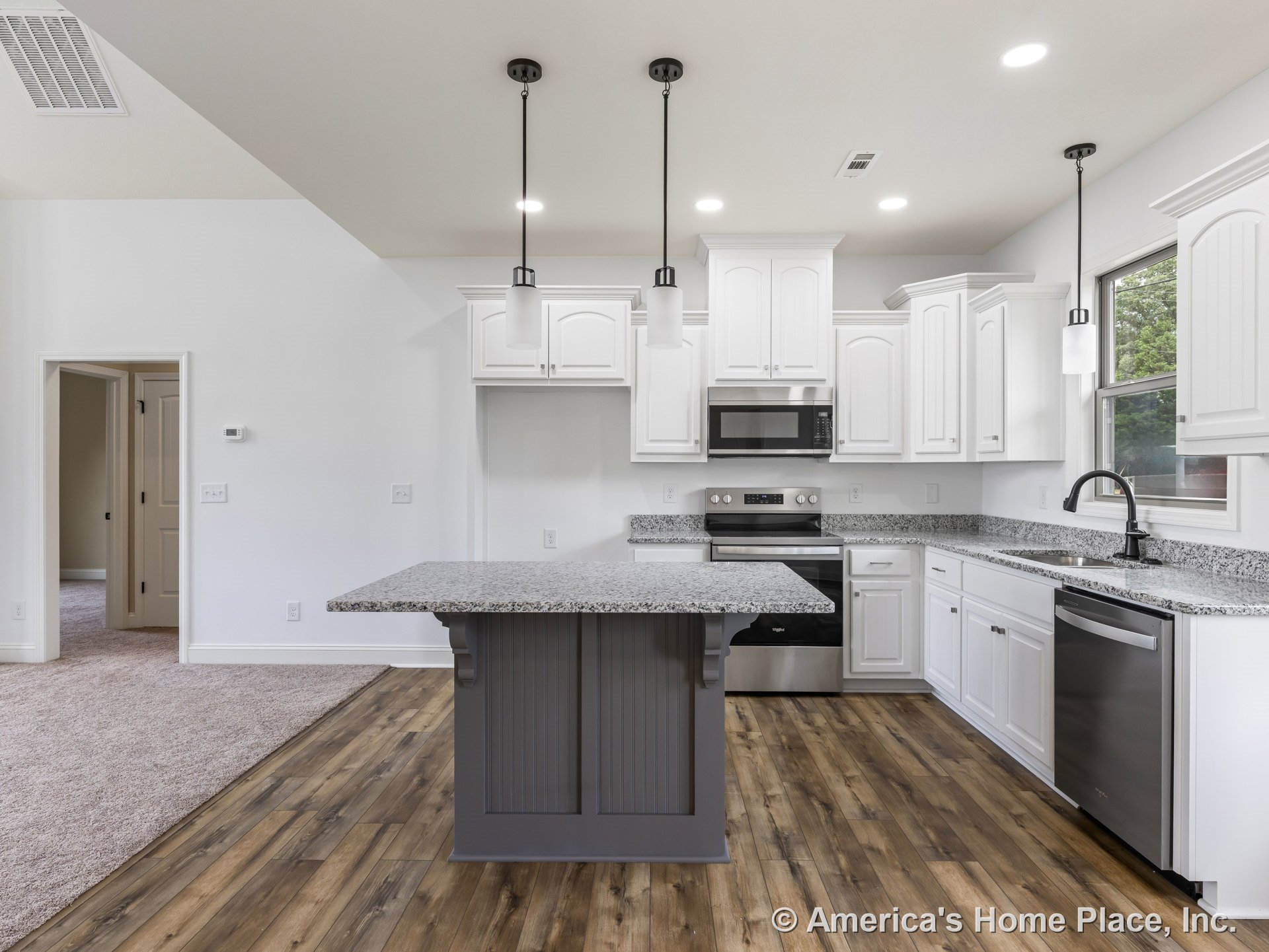 White upper and lower cabinets with granite island countertop, stainless steel oven, built-in microwave, dishwasher, pendant lighting fixtures, wood-look flooring, large window