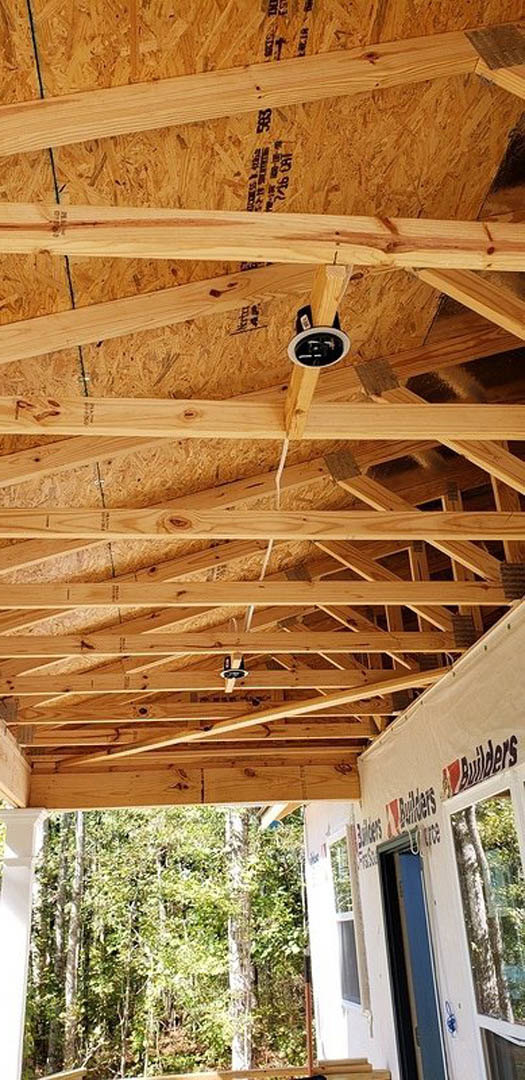 Exposed wooden beams and ceiling with natural wood finish, highlighting roof structure and insulation in a residential home
