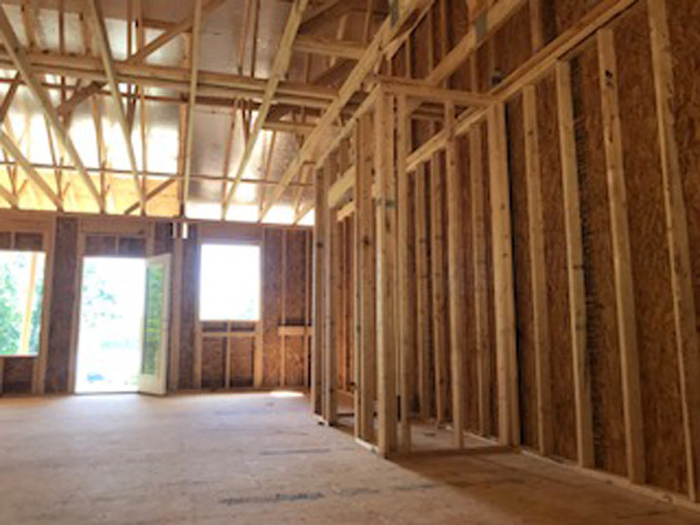 Living room with exposed wood ceiling beams, hardwood floor, white walls, and a wooden door.