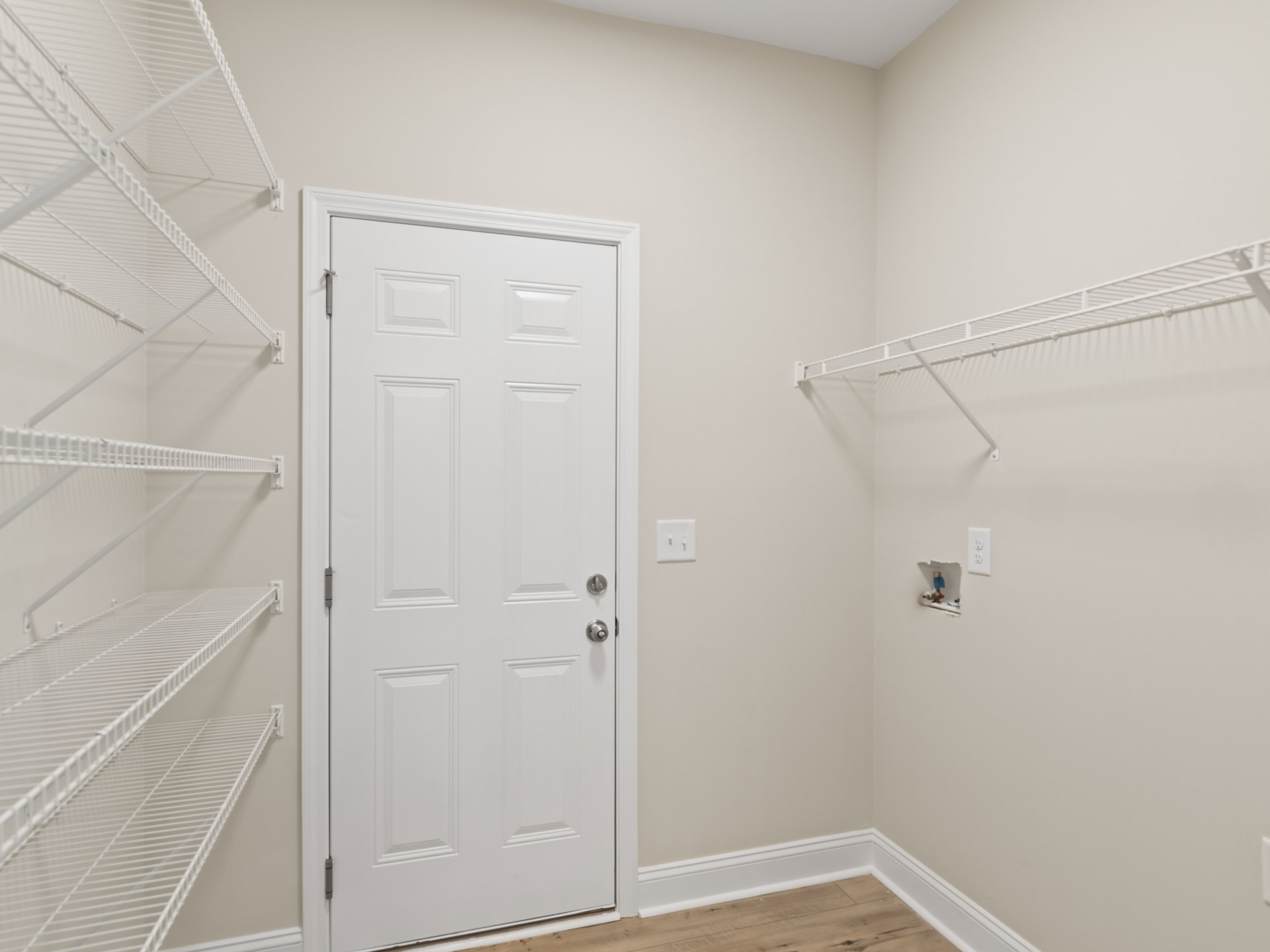 White paneled door with silver knobs, built-in white shelves on adjacent wall, plaster walls, crown molding, and a blurry light switch.