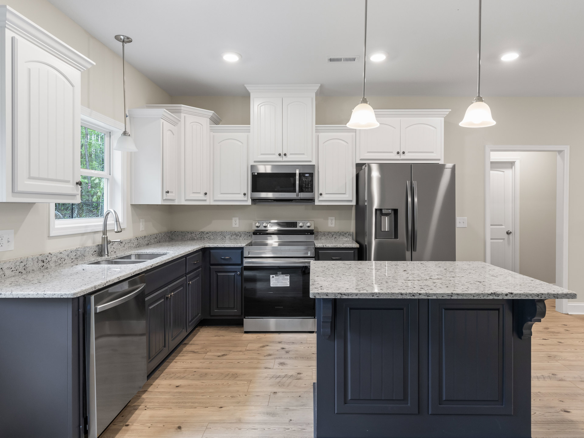 Kitchen with granite countertops, stainless steel appliances including microwave, stove with warning sign, refrigerator with water dispenser, marble-topped island, wood cabinetry