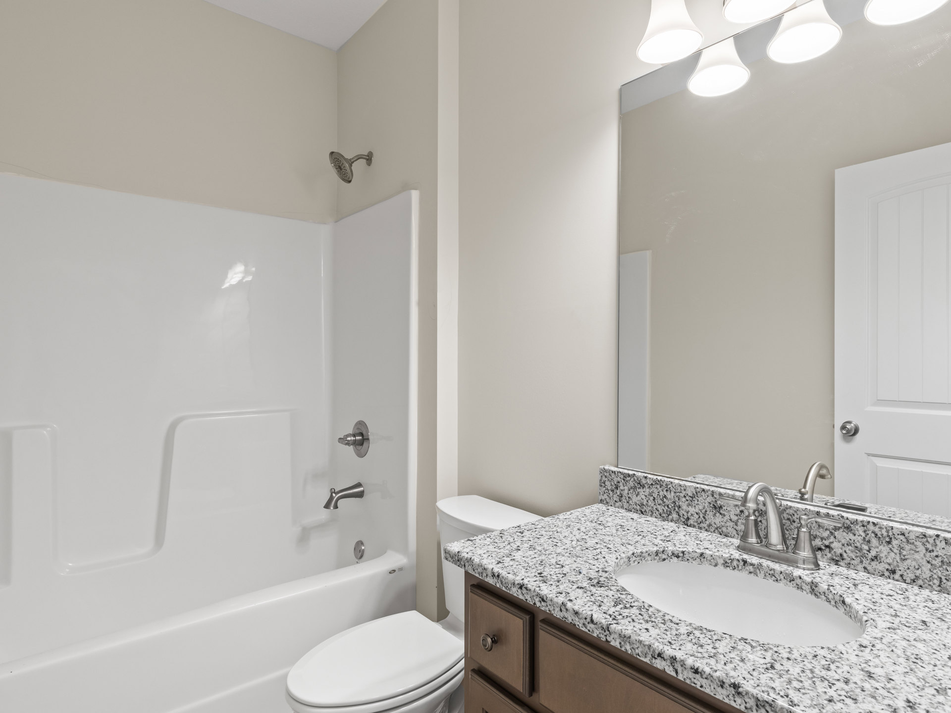 White bathroom with rectangular sink and chrome faucet, modern toilet, built-in bathtub with tiled surround, and wall-mounted showerhead.