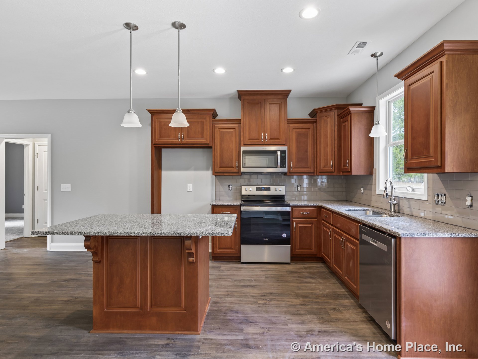 Wood cabinetry kitchen with granite island countertop, stainless steel oven and microwave, tile backsplash, pendant lighting fixtures, large window above sink, and hardwood