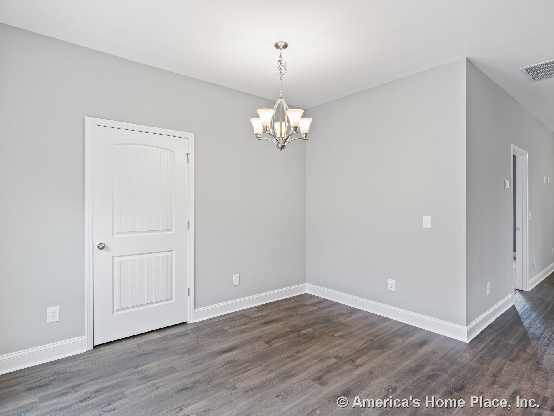 Dining area with modern chandelier, white paneled interior door, gray painted walls, wood-look vinyl plank flooring, white baseboard trim, and room corner featuring electrical