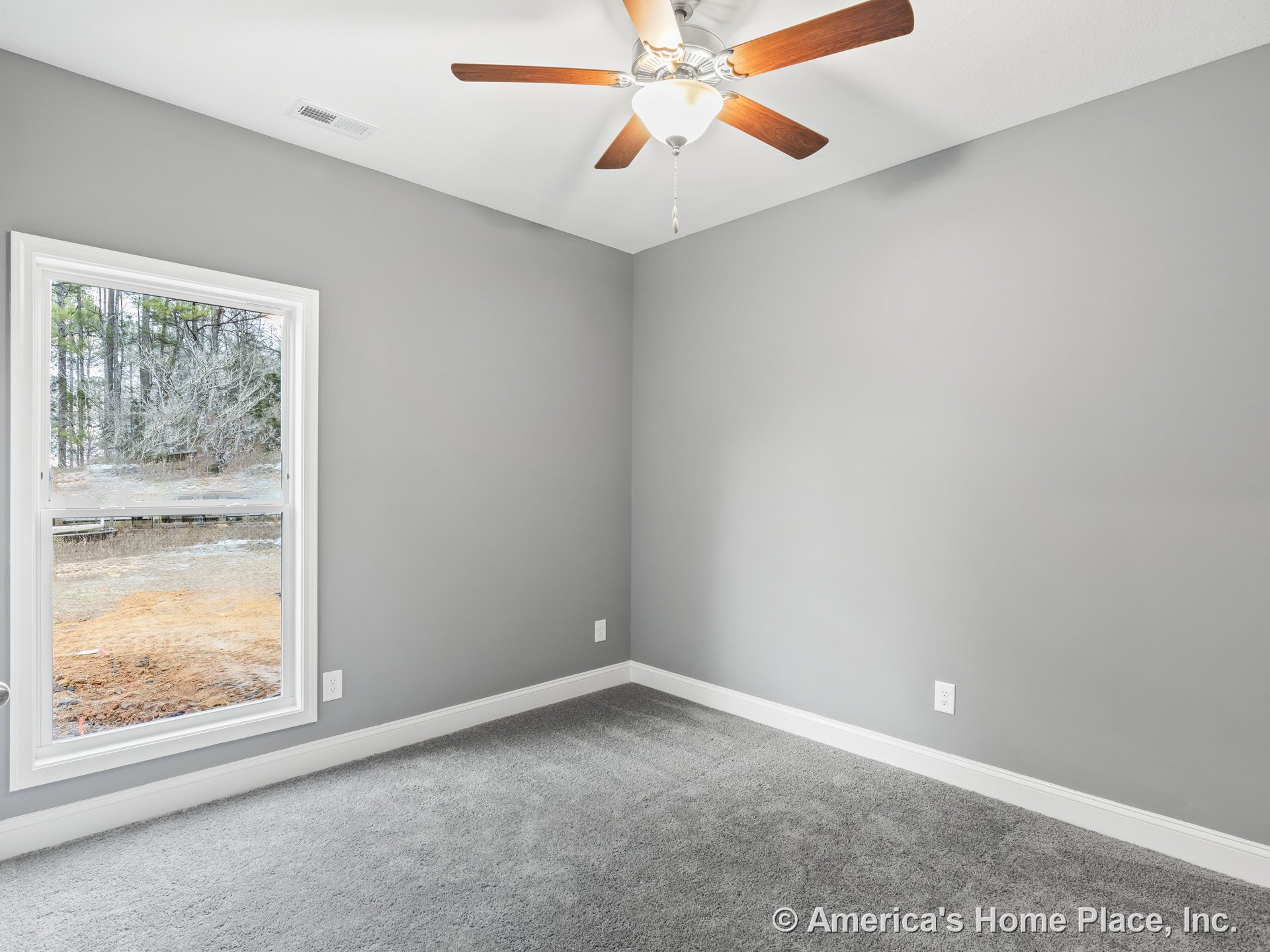 Bedroom with gray carpet flooring, light gray walls, large window framed in white trim, ceiling fan with wooden blades and light fixture, white baseboards, and single electrical