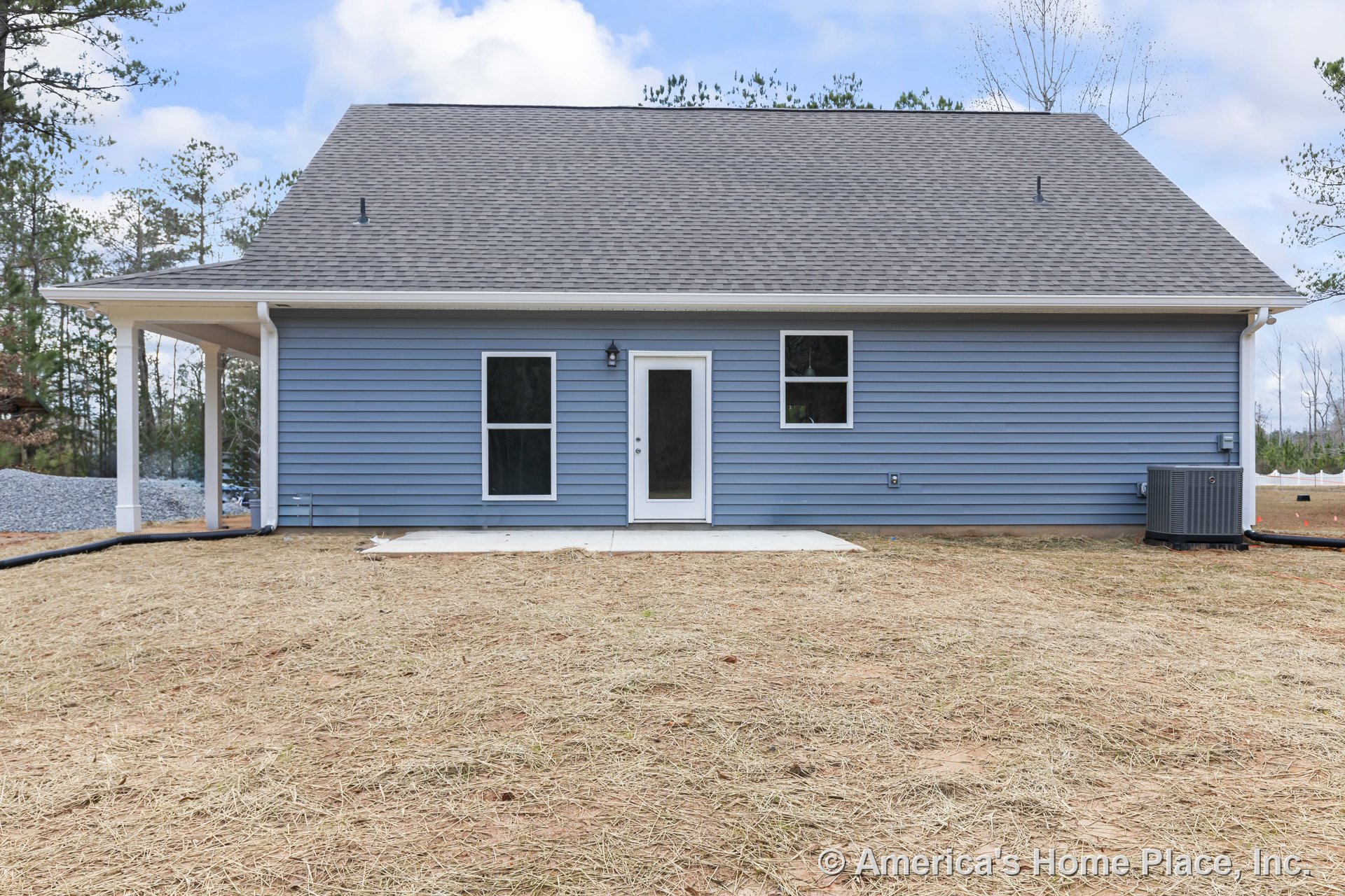 Blue vinyl siding exterior with white trim, gable roof, covered porch, concrete patio, double-hung windows, back door, outdoor lighting, HVAC unit, and downspouts.