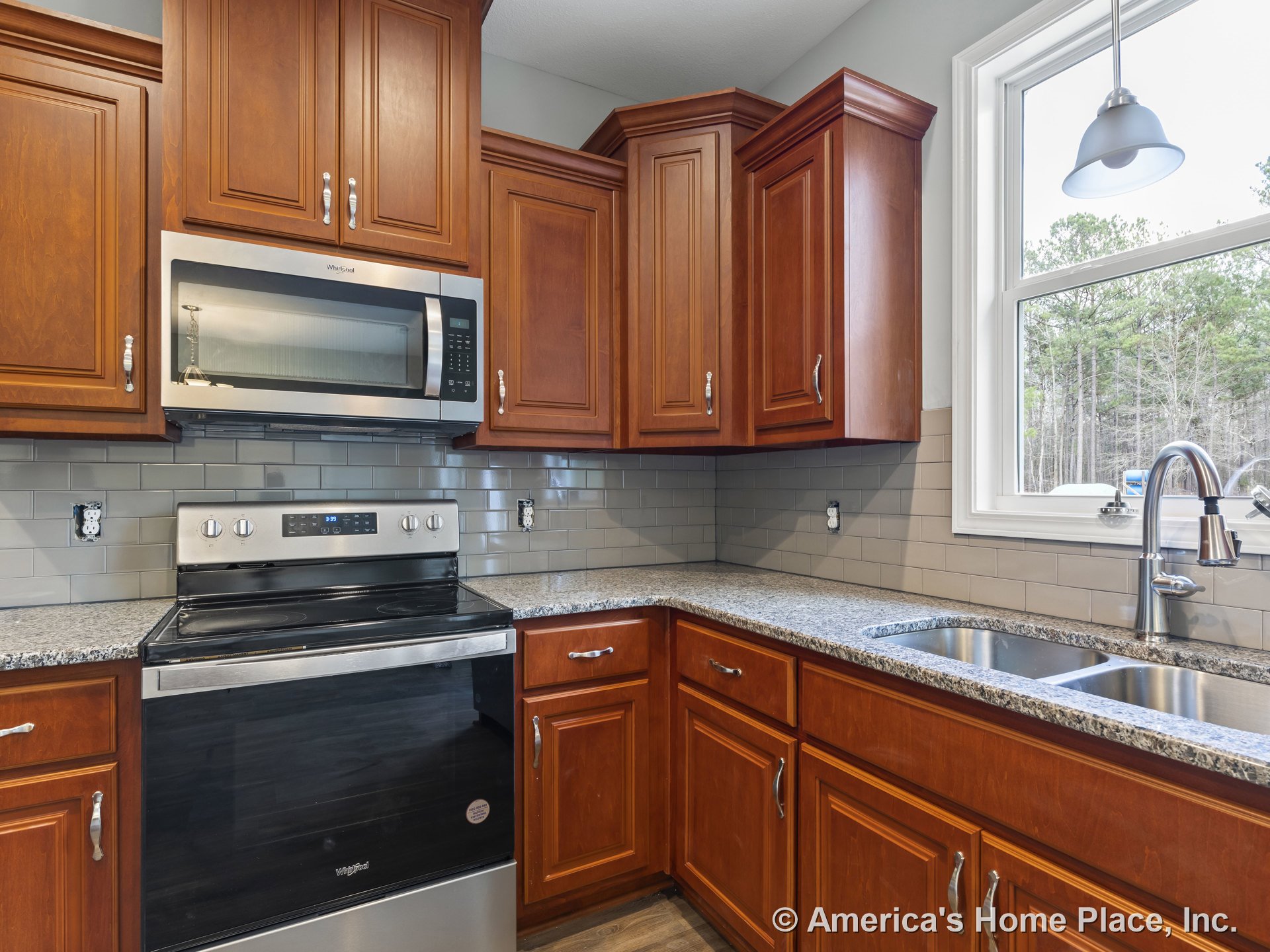 Raised panel wood cabinetry with upper and lower storage, granite countertops, stainless steel electric range and microwave, subway tile backsplash, double bowl undermount sink