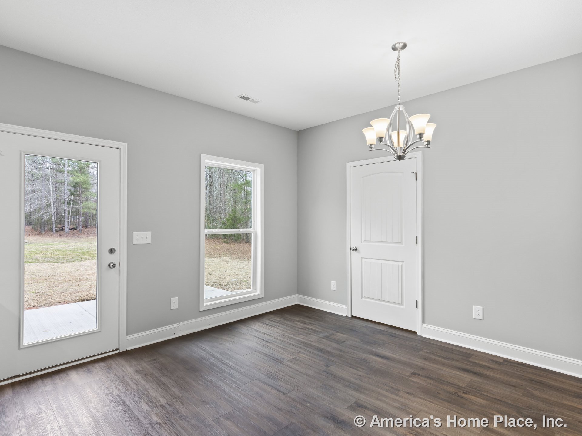 Dining area with wood-look plank flooring, modern chandelier, large window and glass exterior door, white trim and baseboards, paneled interior door, neutral wall color, and
