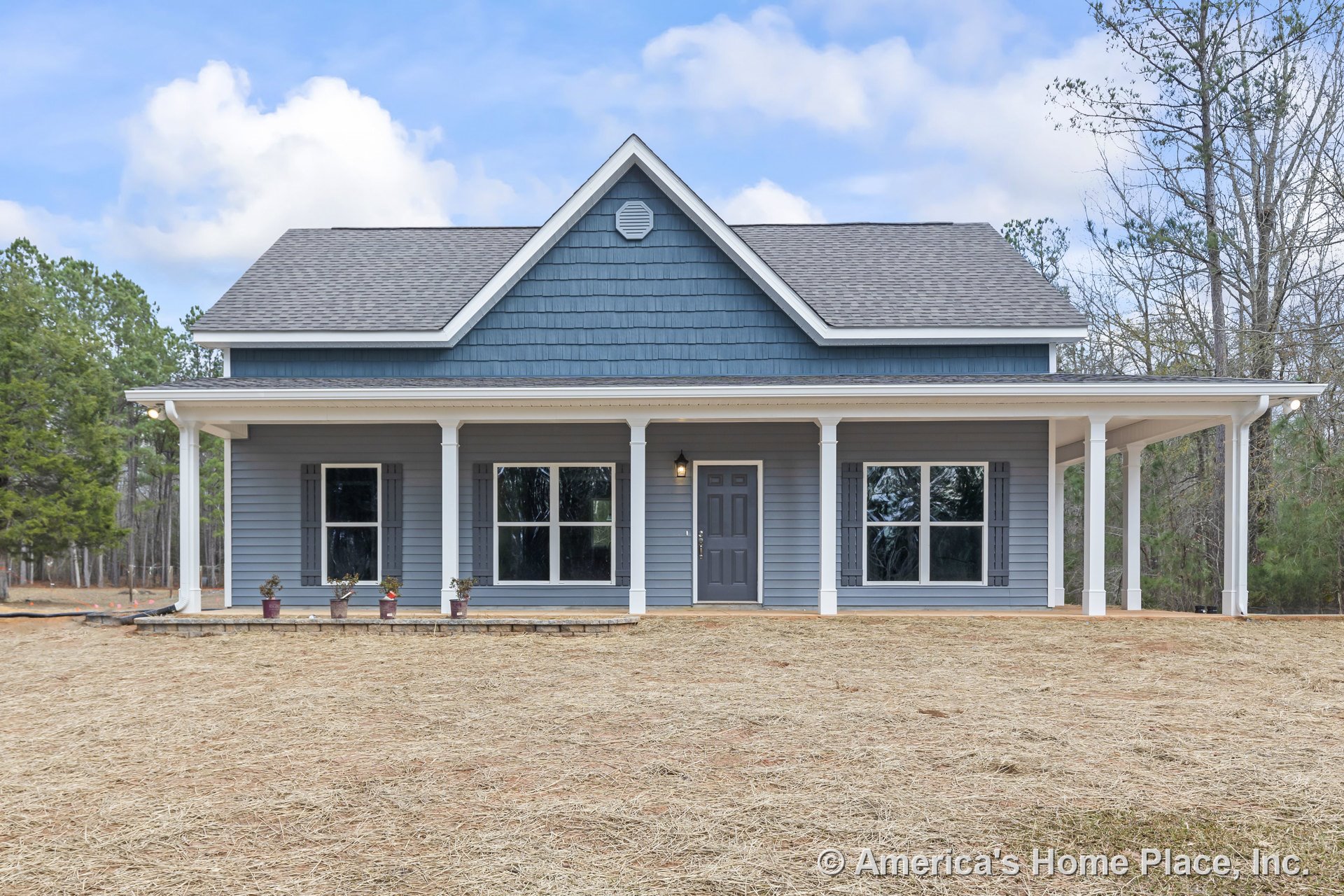 Covered front porch with white columns, blue lap siding, large front windows, central front door, gable roof, white trim, and decorative shutters.