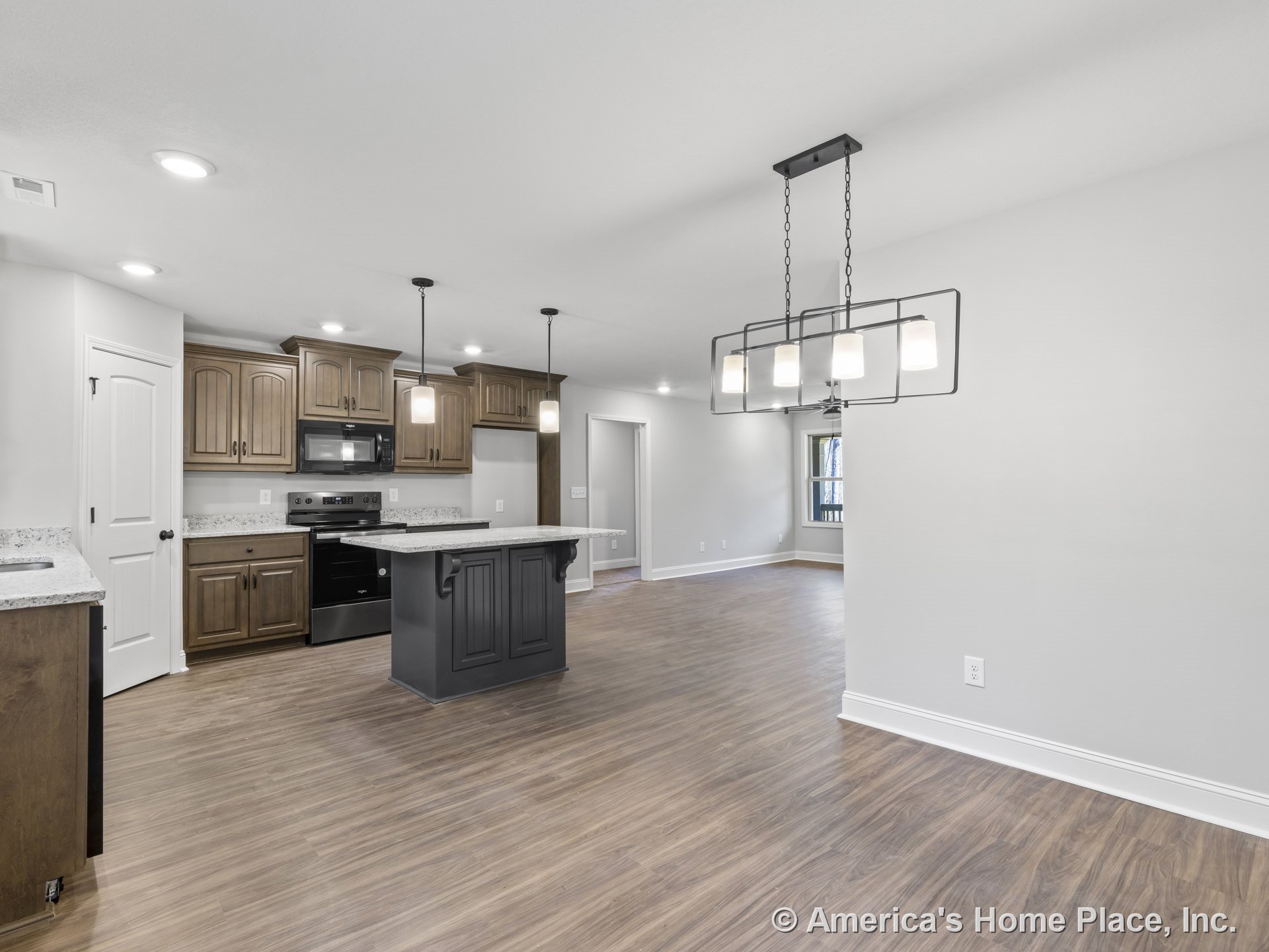 Open kitchen with wood cabinetry, granite countertops, black central island, pendant and chandelier lighting, wood-look flooring, recessed lighting, windows, and interior doors.