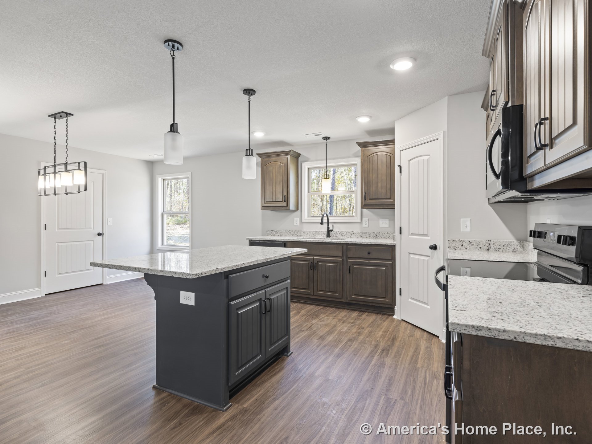 Dark wood kitchen cabinets with granite countertops, central island beneath pendant lights, wood-look flooring, double window above sink, built-in appliances, recessed lighting