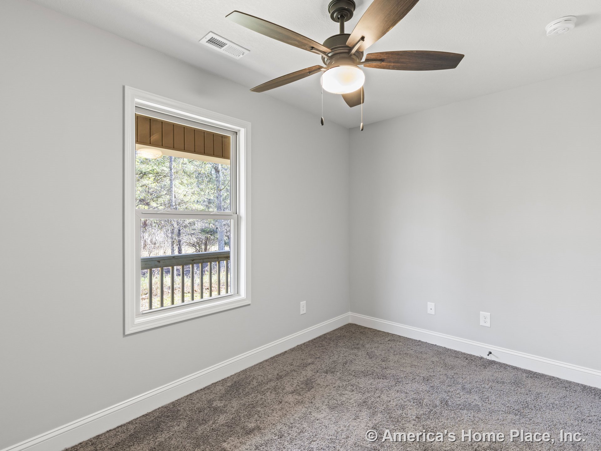 Bedroom with ceiling fan and light fixture, single window with white trim, neutral wall color, carpet flooring, baseboard molding, wall outlet, and smoke detector.