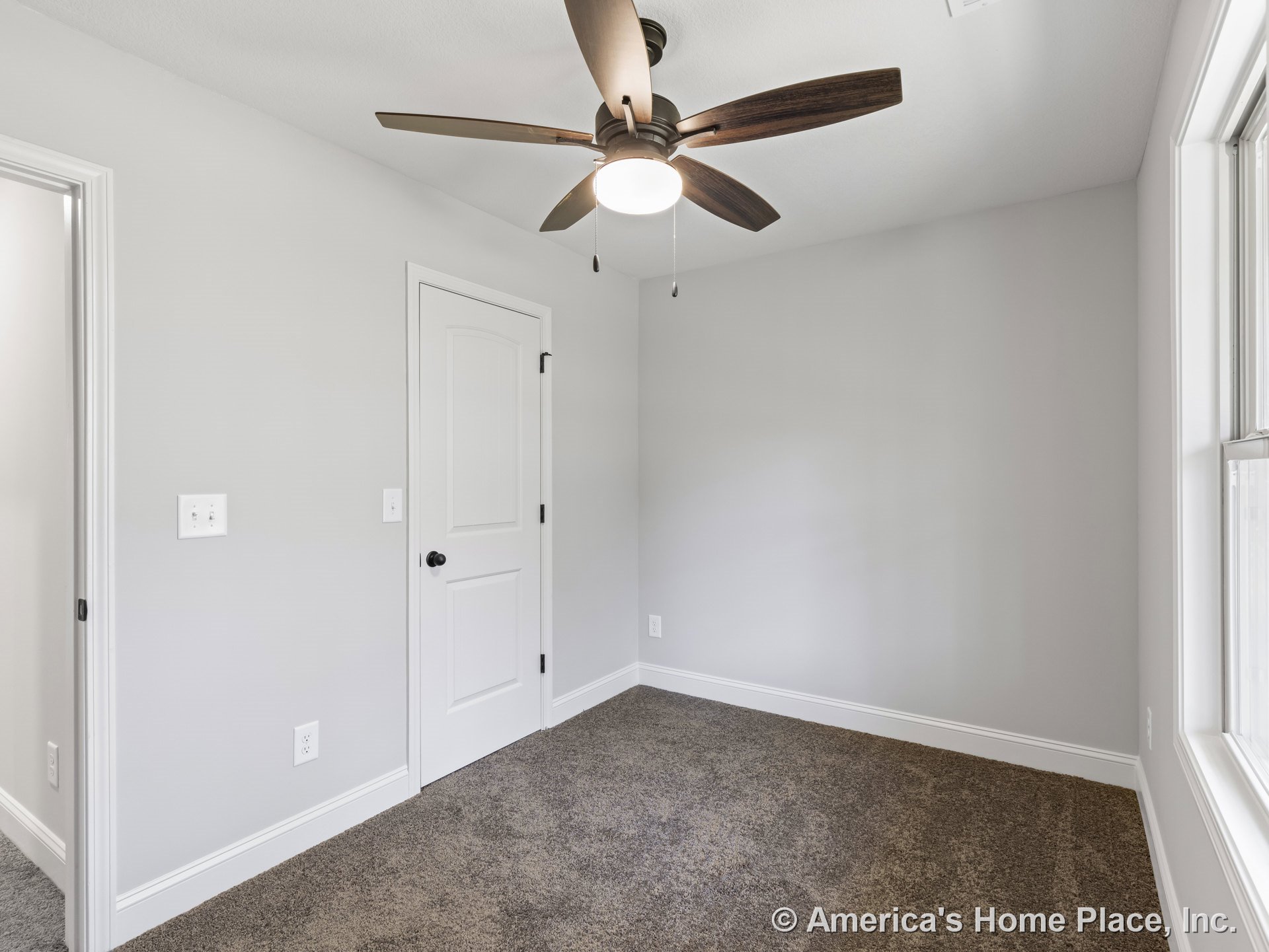 Bedroom with carpet flooring, ceiling fan and light fixture, large window allowing natural light, white trim and baseboards, neutral wall color, and white paneled closet door.