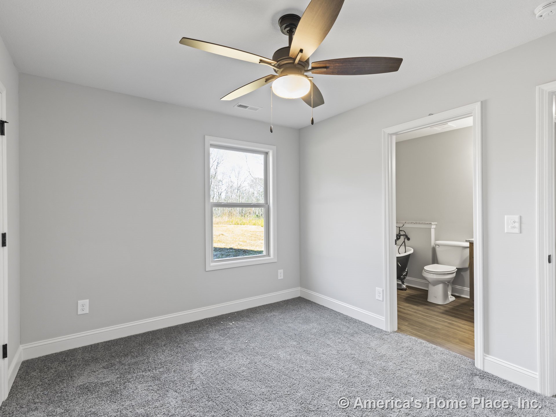 Bedroom with gray carpet, white trim and baseboards, single window with white frame, ceiling fan with integrated light, neutral wall paint, and open doorway leading to bathroom