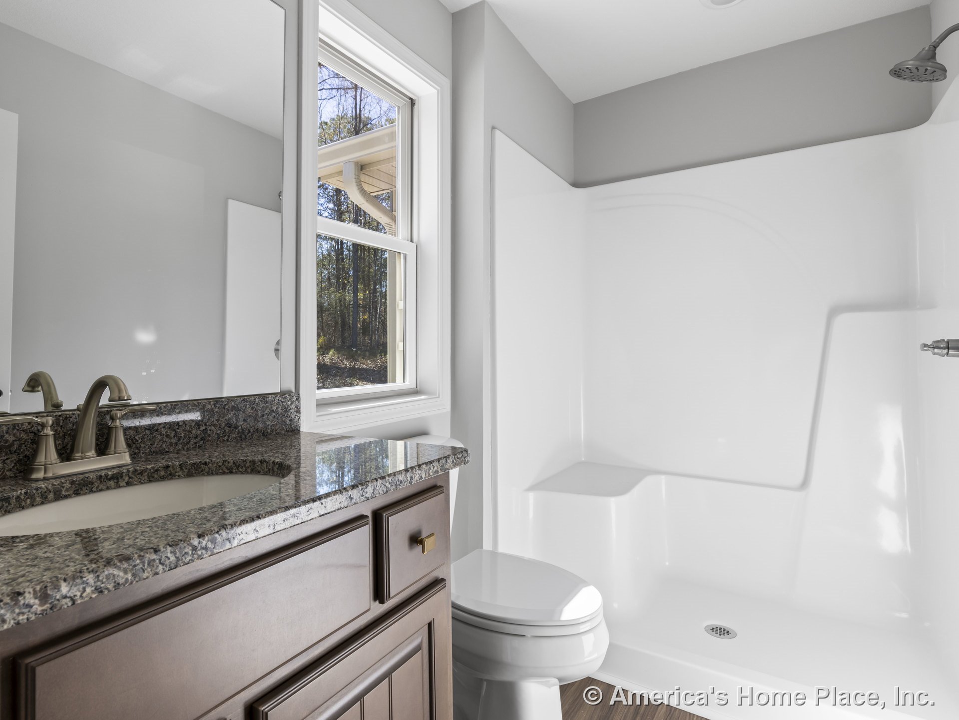 Granite countertop vanity with single-handle faucet, walk-in shower featuring built-in seat, wood-look flooring, white trim window, recessed ceiling light, and cabinetry.